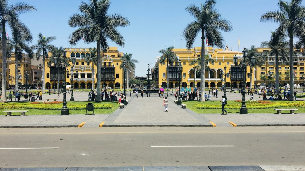 Plaza de Armas in Lima, Peru, with palm trees and people walking on a sunny day