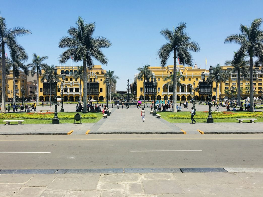 Plaza de Armas in Lima, Peru, with palm trees and people walking on a sunny day