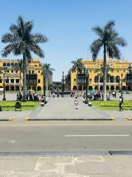 Plaza de Armas in Lima, Peru, with palm trees and people walking on a sunny day