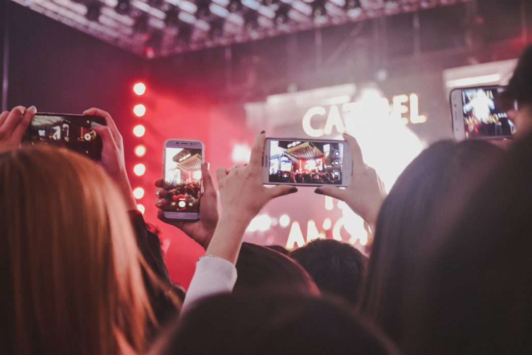 Concertgoers filming a night rock show in Buenos Aires on their phones, illustrating Indio Solari