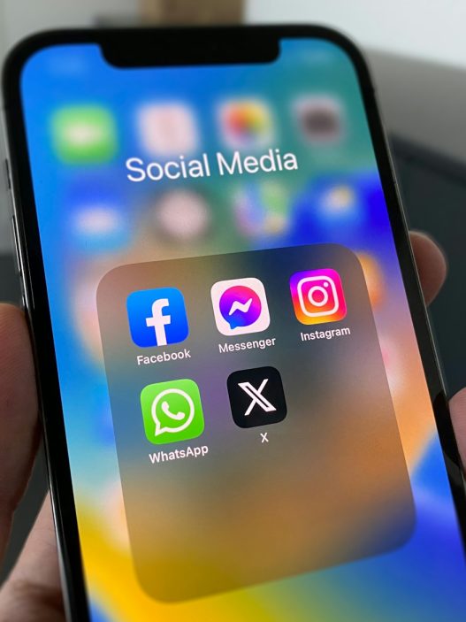 Hand holding a phone with social media apps including X, how to retweet