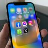 Hand holding a phone with social media apps including X, how to retweet